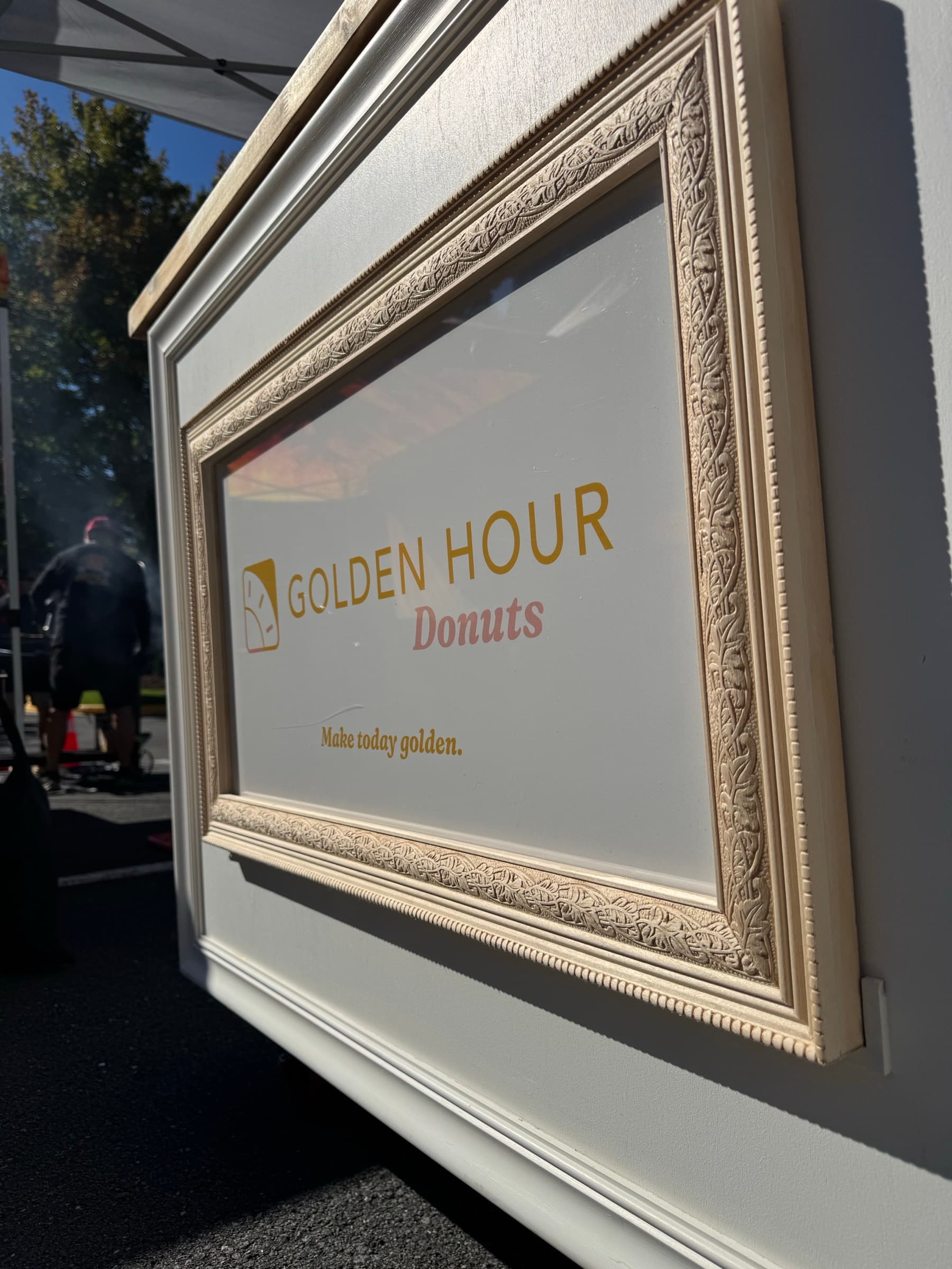 The framed Golden Hour Donuts sign on the front of the cart