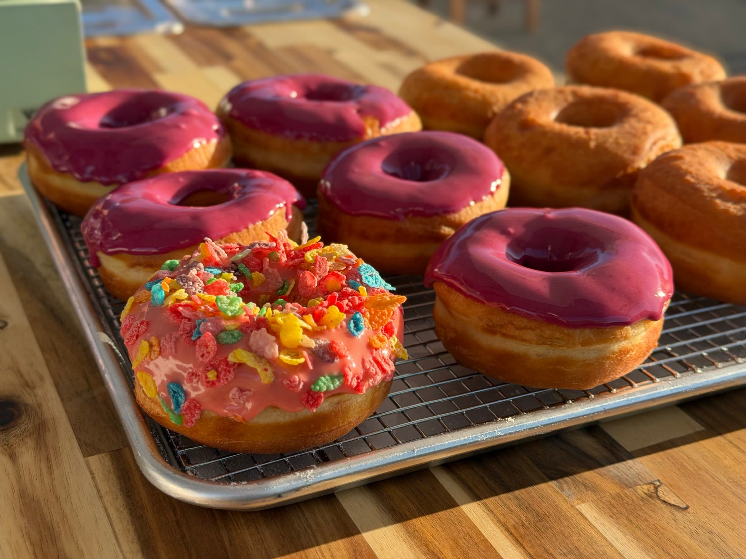 Glazed donuts and a cereal-topped donut on a cooling rack