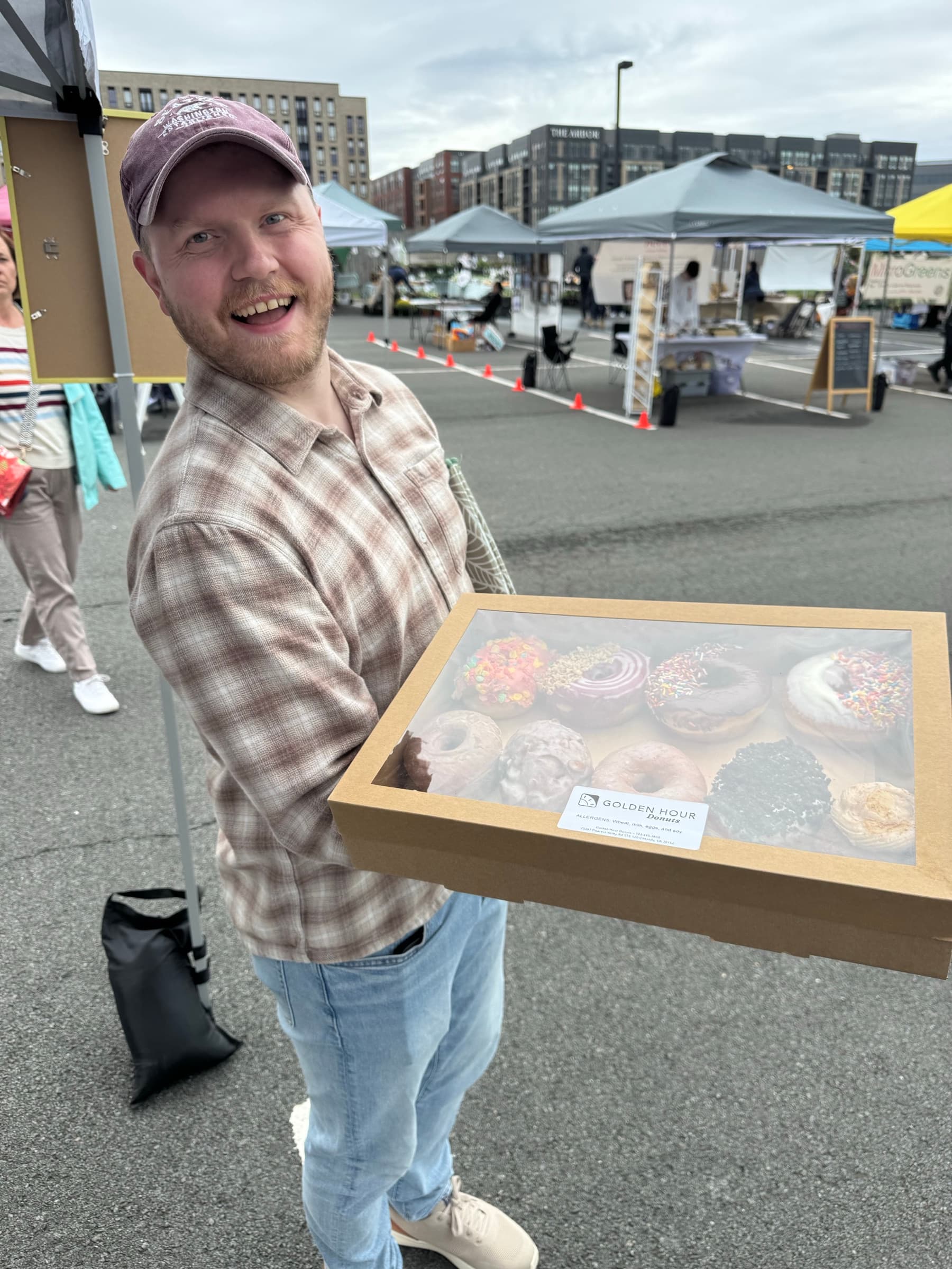 A smiling guest holding a full box of donuts